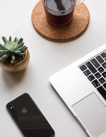 top view of a table with a cactus, phone, laptop and coffee